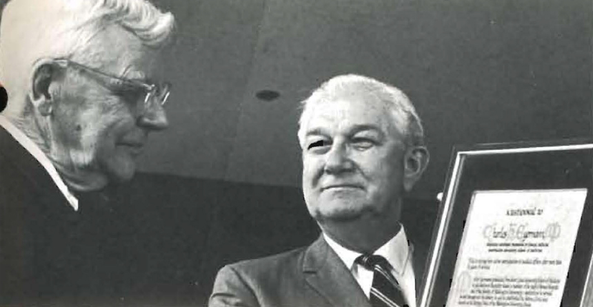 A photo of Dr. Stanley Hampton receiving a plaque honoring him at his retirement from Dr. Stanley Hampton