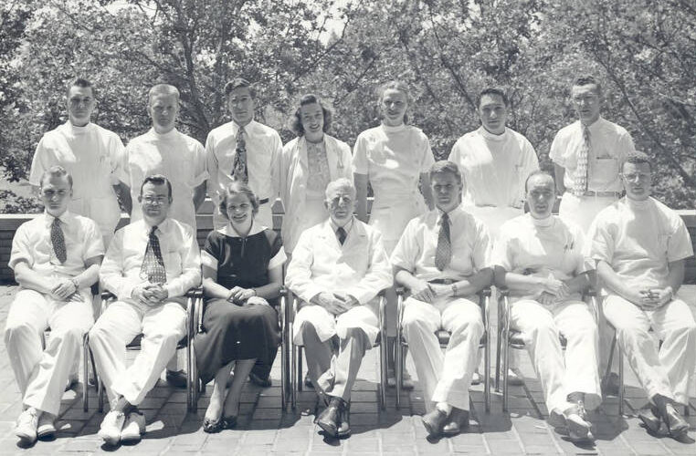 A photo of Dr. Harry Alexander seated in the middle of a group of unnamed staff members in 1951