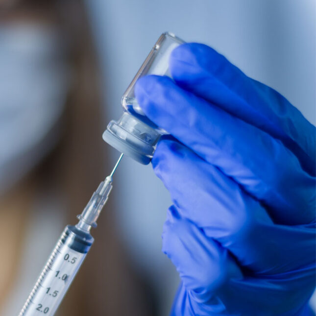 Vaccine in researcher hands, female doctor holds syringe and bottle with vaccine for coronavirus cure. Concept of corona virus treatment, injection, shot and clinical trial during pandemic.